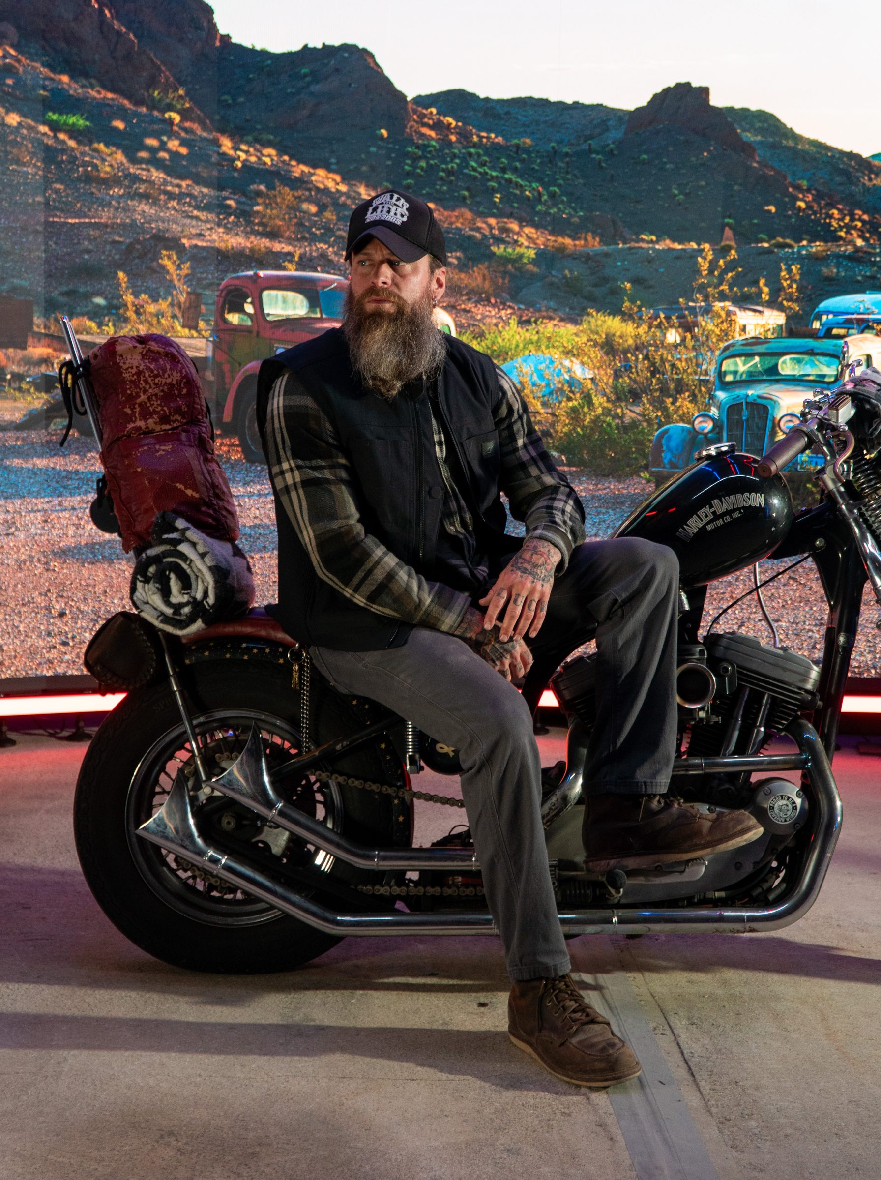 Bearded rider seated on a custom motorcycle in the desert