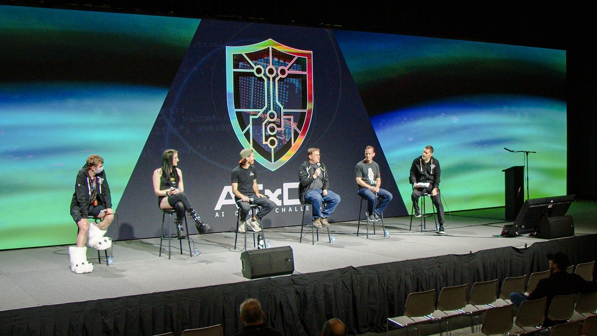 Panel on stage in front of the AIxCC shield