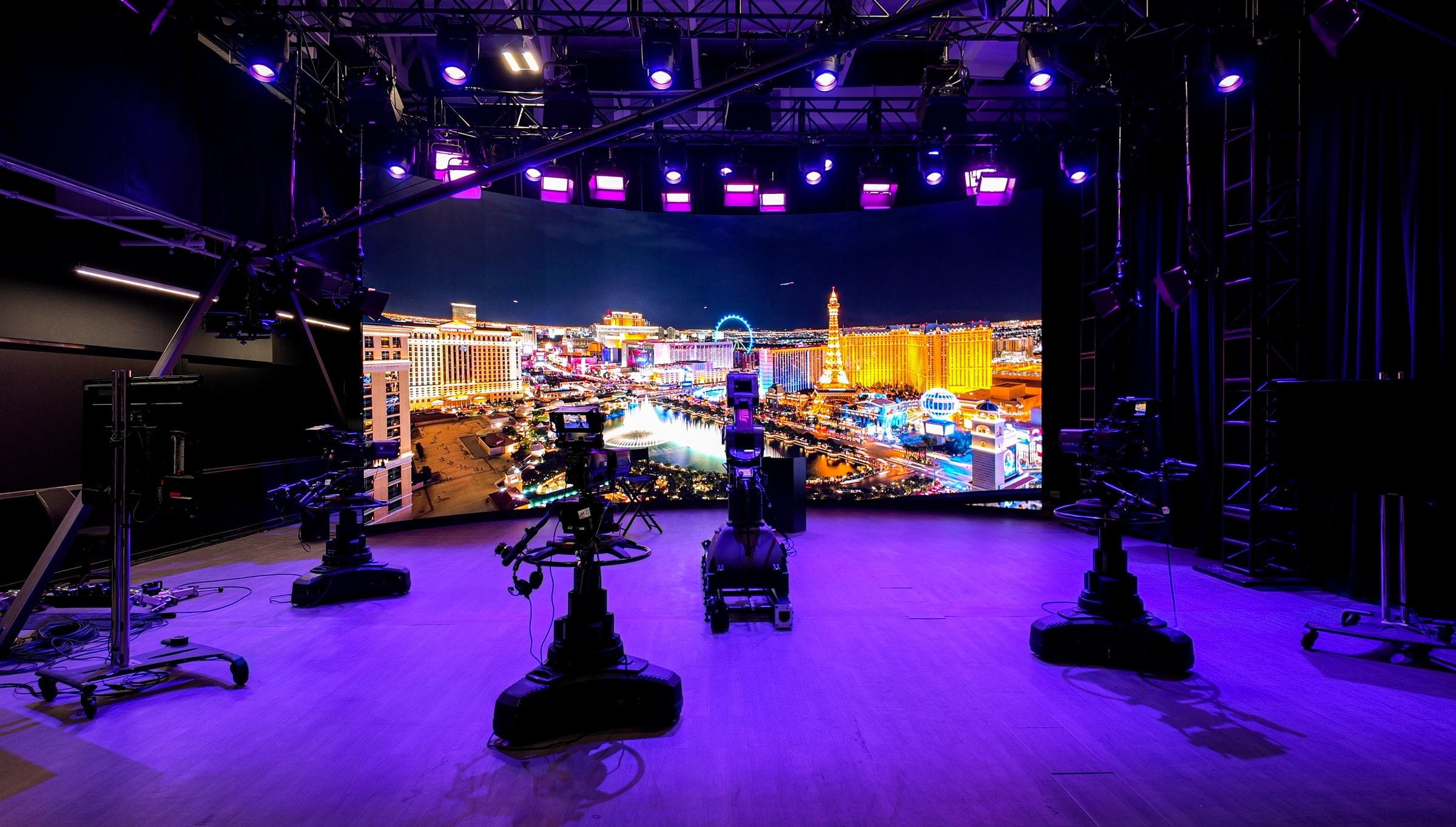 Pedestal cameras on the purple-lit stage facing an LED wall showing the Las Vegas Strip
