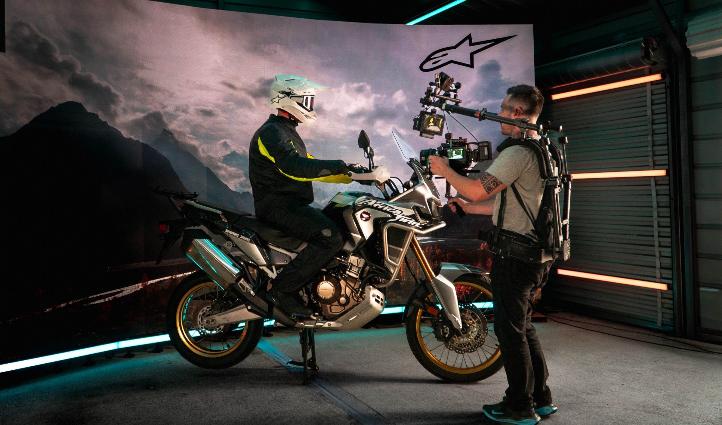 Operator on a stabilized rig filming a rider on an adventure bike in front of the LED wall