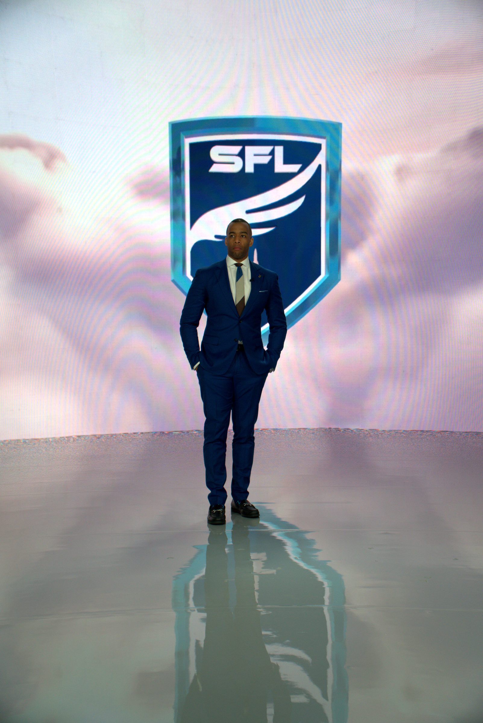 Host in a blue suit in front of the SFL shield on the XR stage