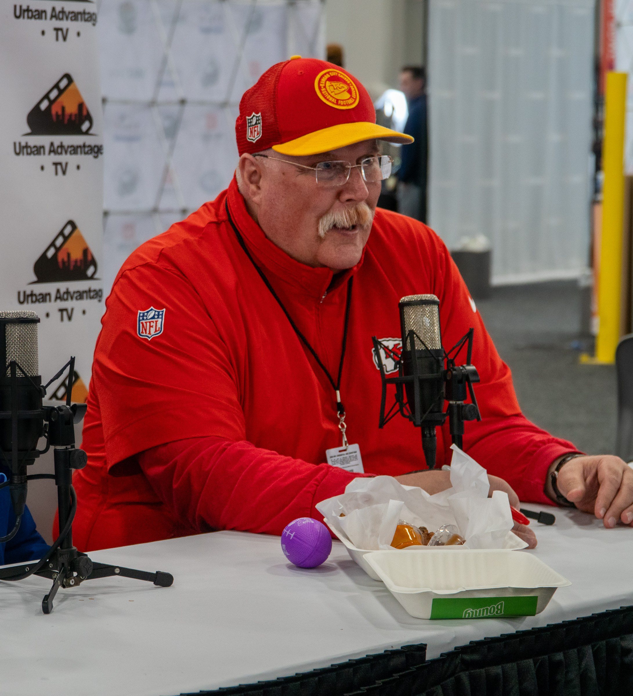 Coach in Chiefs red at a Radio Row microphone